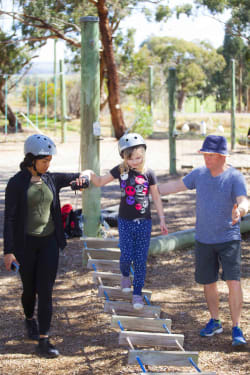 Img: Girl supported by volunteers on low ropes course